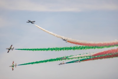 a group of airplanes flying in formation with colored smoke behind them