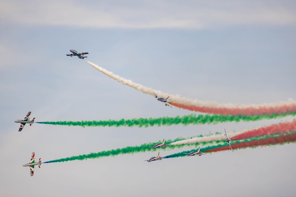 un grupo de aviones volando en formación con humo de colores detrás de ellos