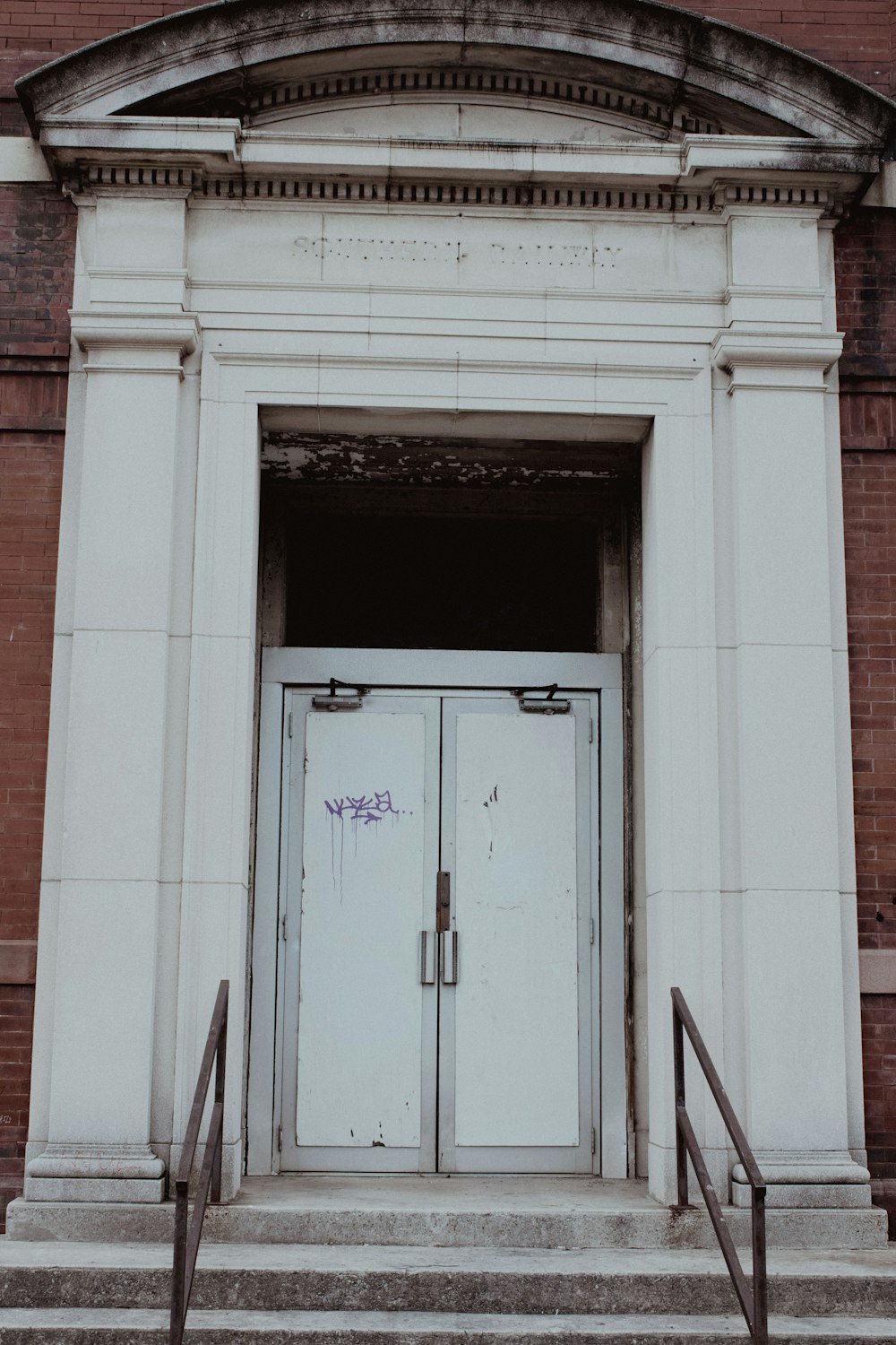 a white building with two doors and some steps