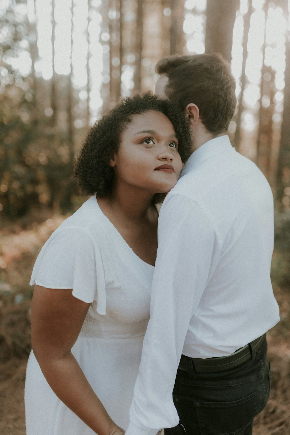 a man and a woman standing in the woods