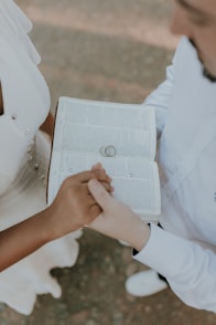 a bride and groom holding hands and holding a book