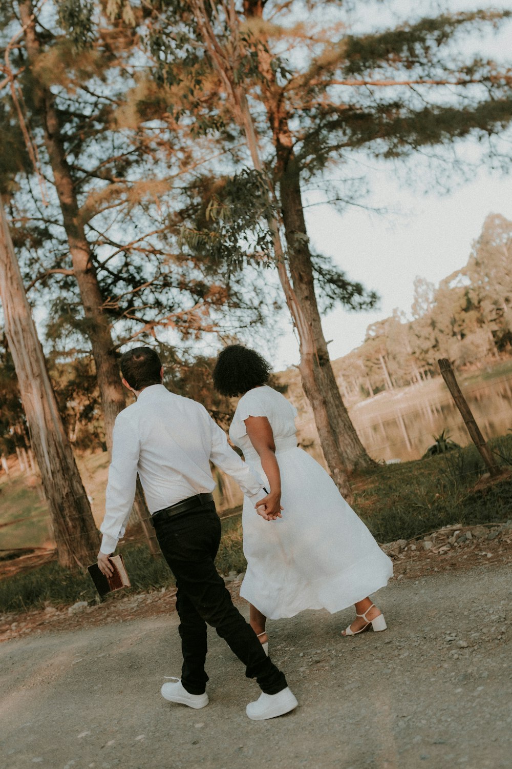 a man and a woman walking down a road holding hands