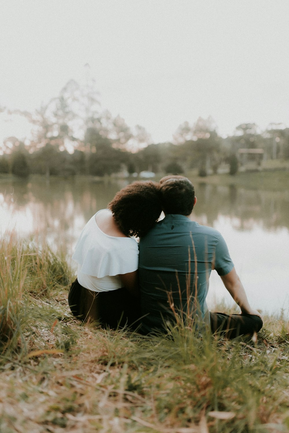 a man and a woman sitting next to a lake