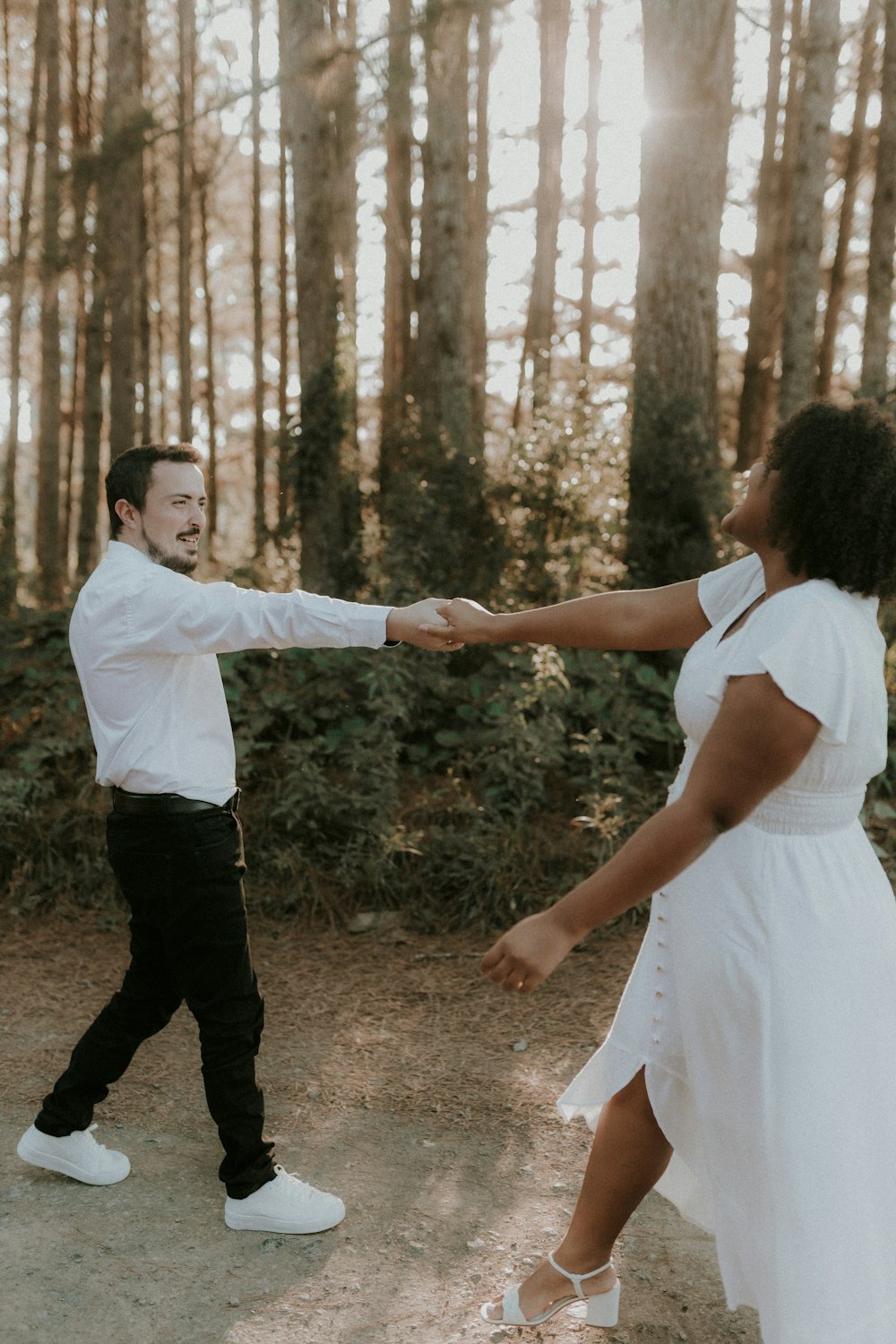 a man and a woman holding hands in the woods