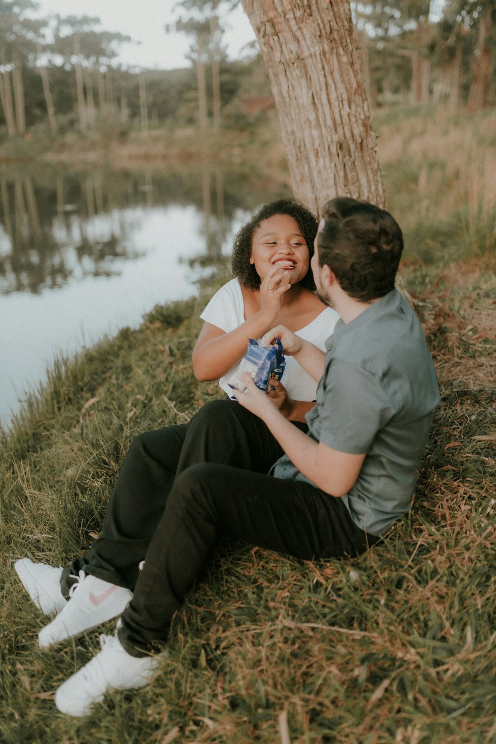 a man and a woman sitting next to a tree