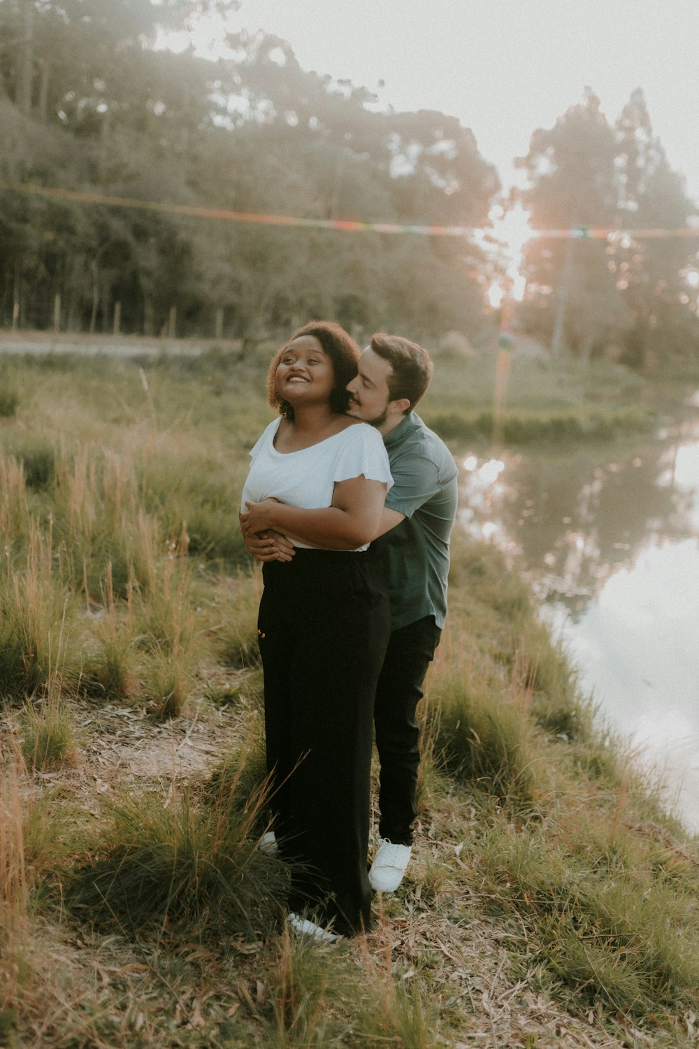 a man and a woman embracing in front of a lake