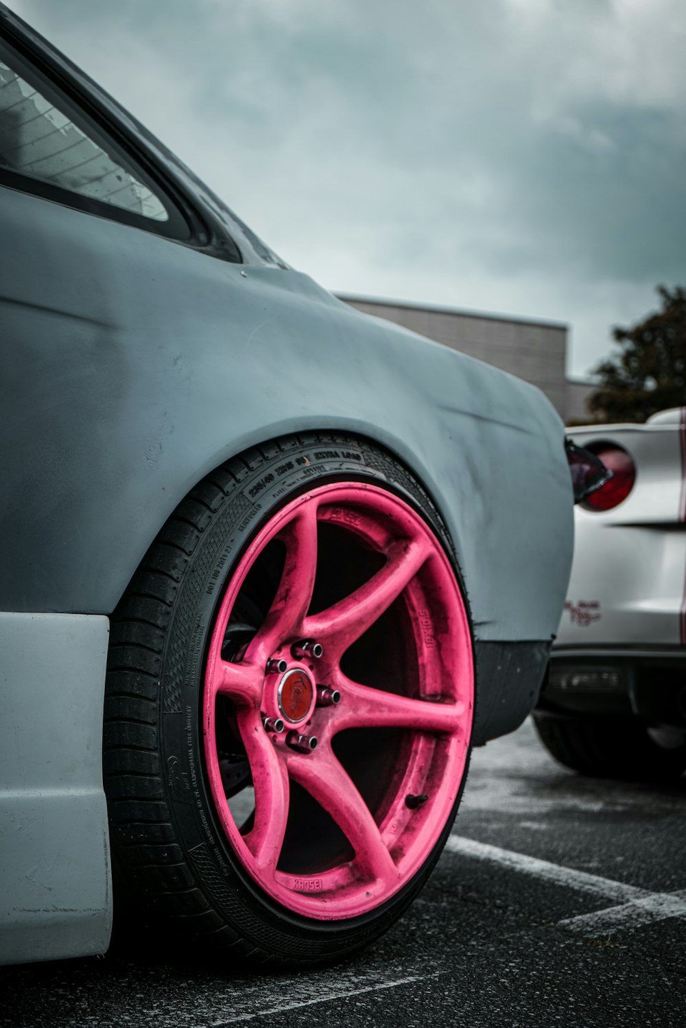 a car with pink rims parked in a parking lot