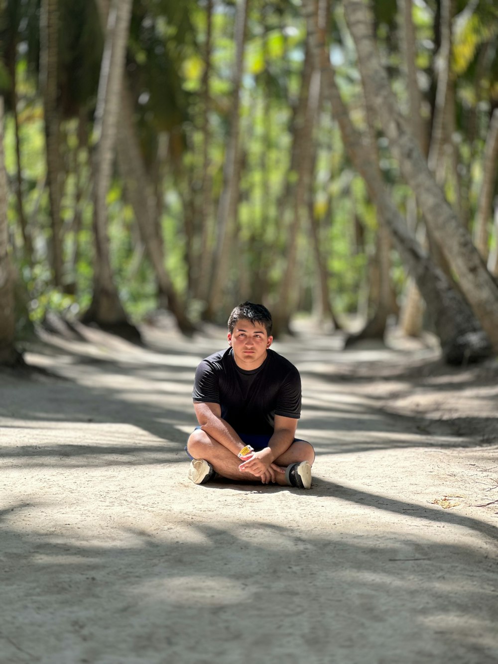 a man sitting on the ground in the middle of a forest