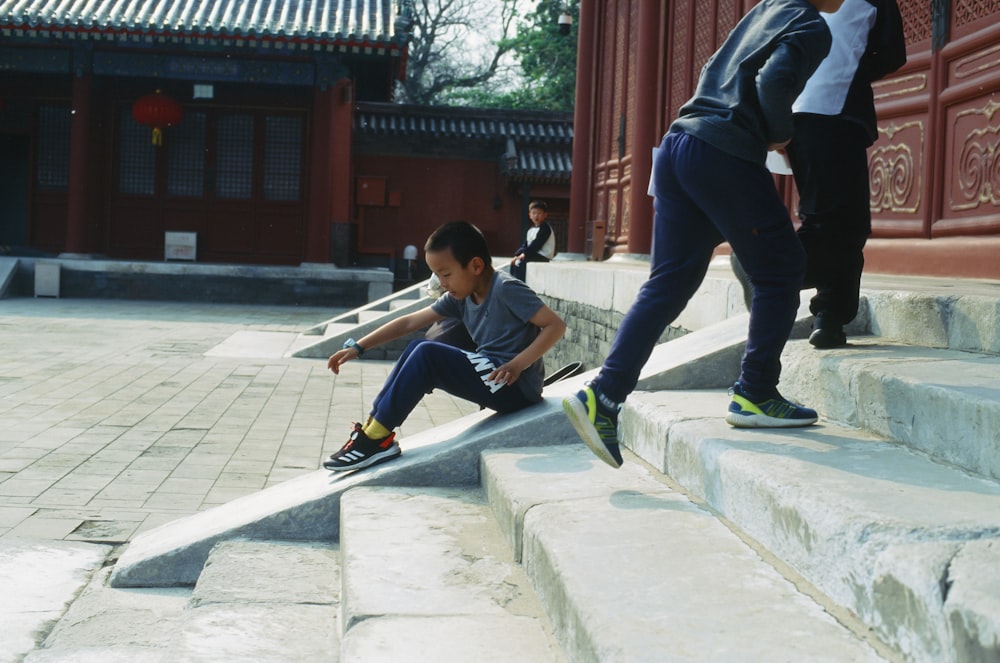 a young boy sitting on the steps with his skateboard