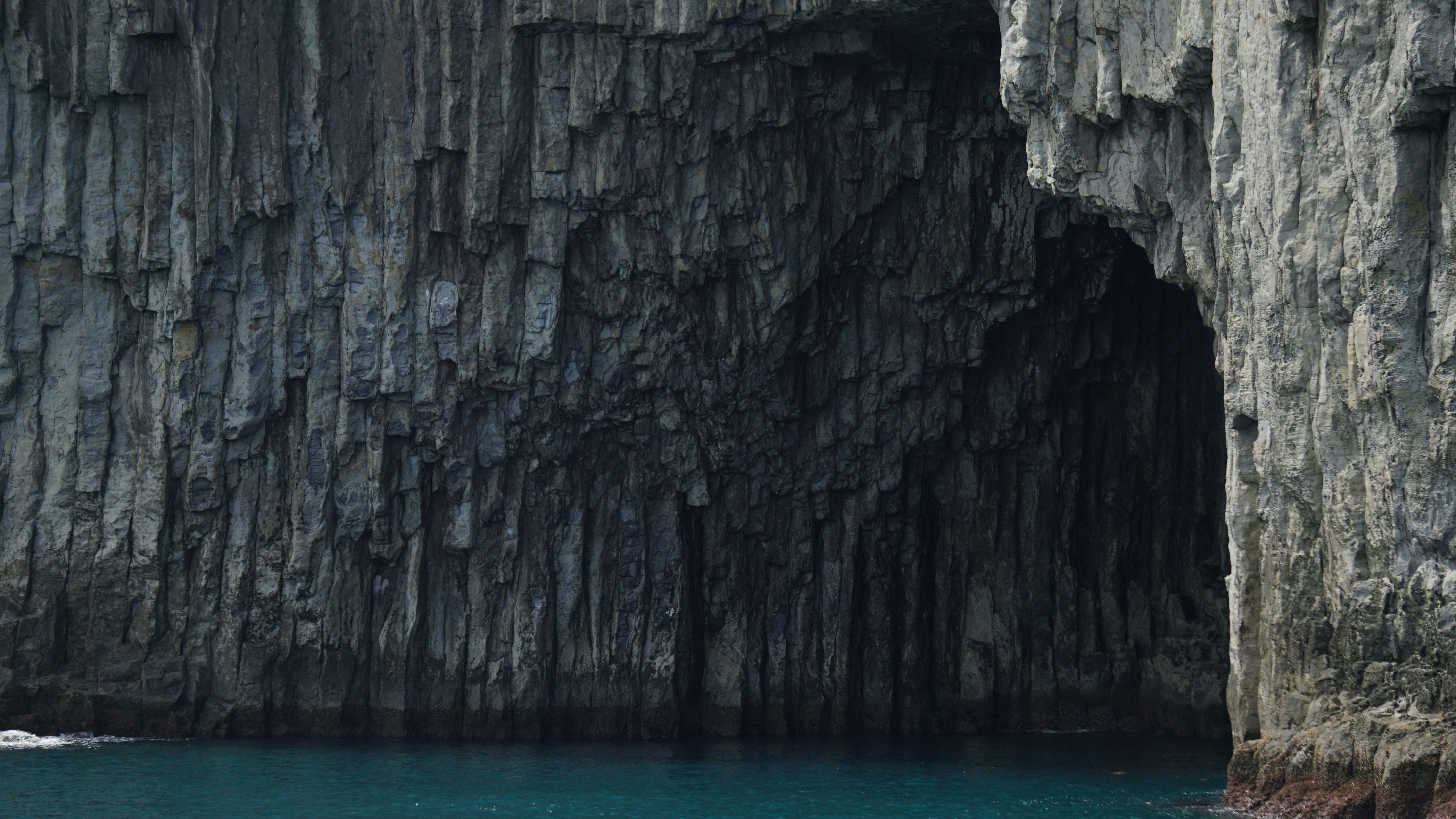 a boat in a body of water near a large rock formation, 