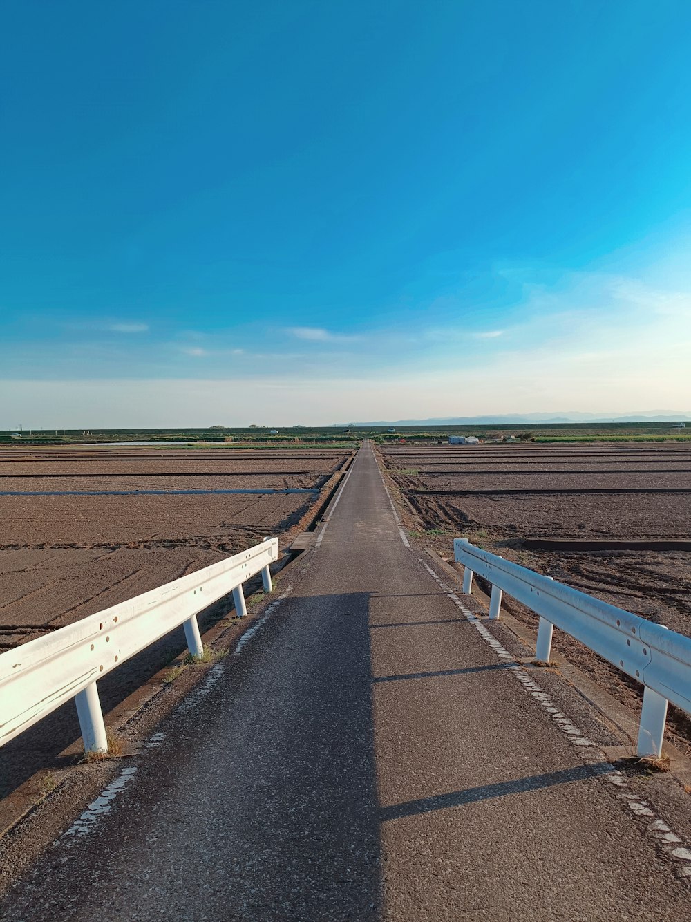 a long road with two white benches on the side of it