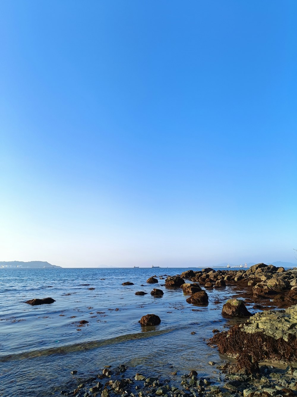 a beach with rocks and water under a blue sky