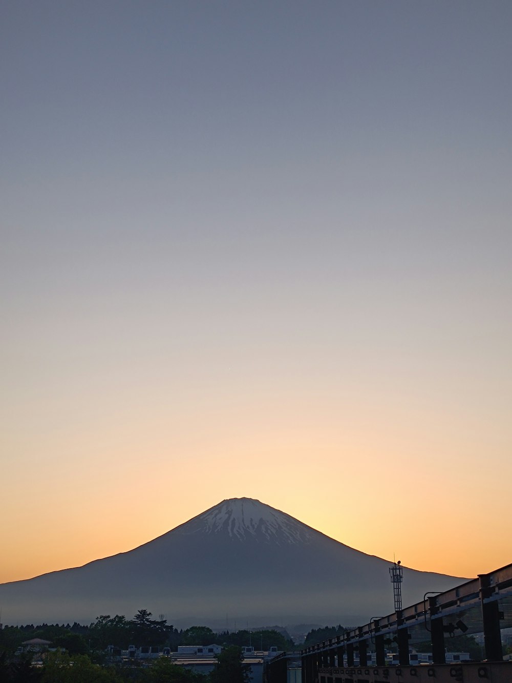 a train traveling past a mountain with a sky background