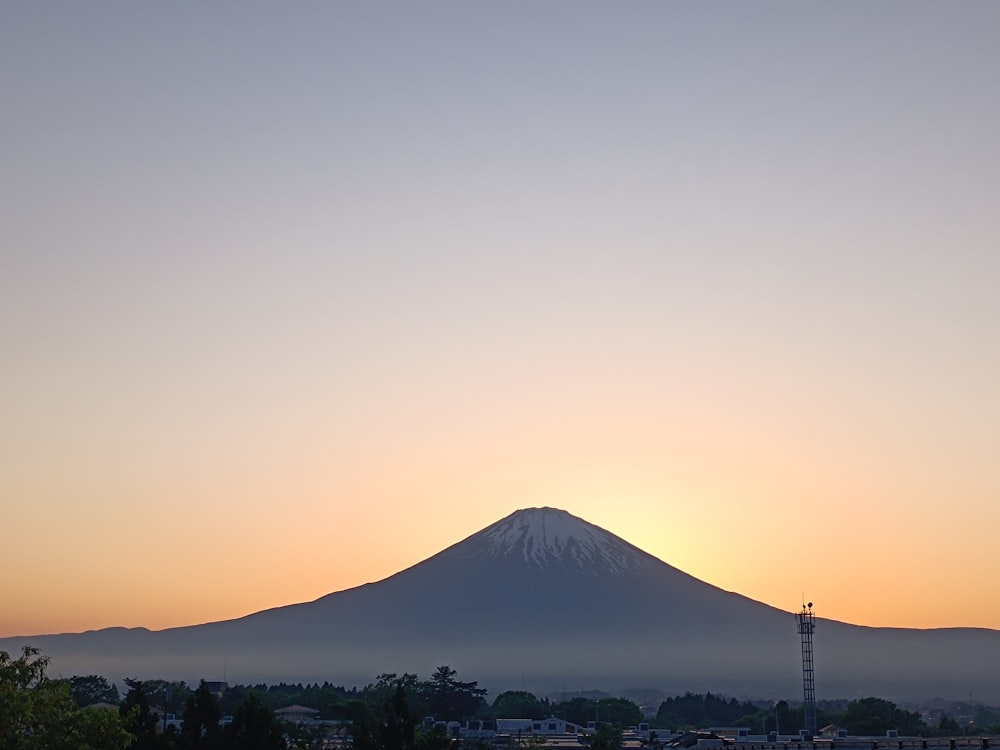 el sol se está poniendo detrás de una montaña en la distancia