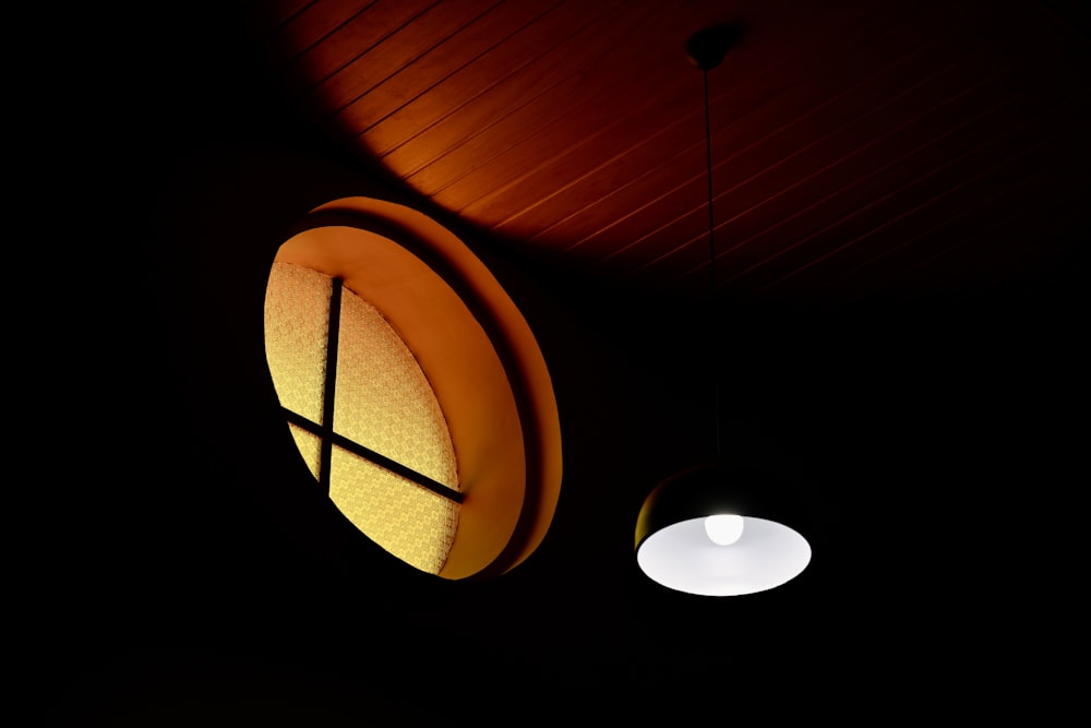 a round light hanging from a ceiling in a dark room