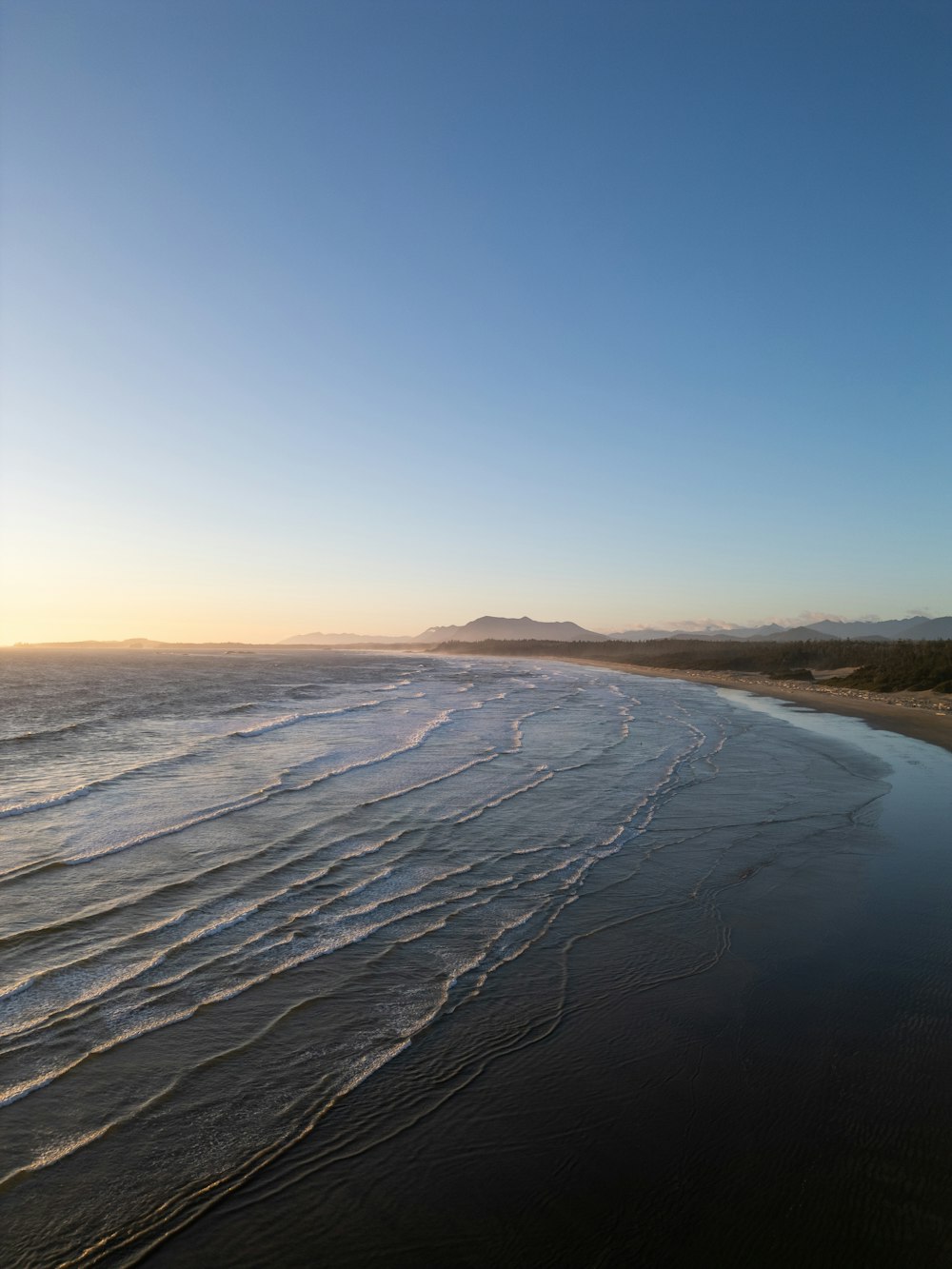 a view of a beach with waves coming in from the ocean