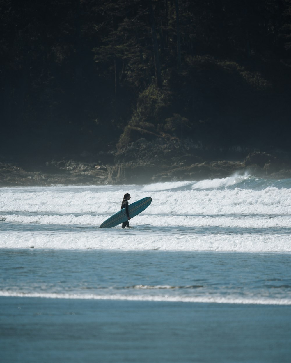 uma pessoa andando na água com uma prancha de surf