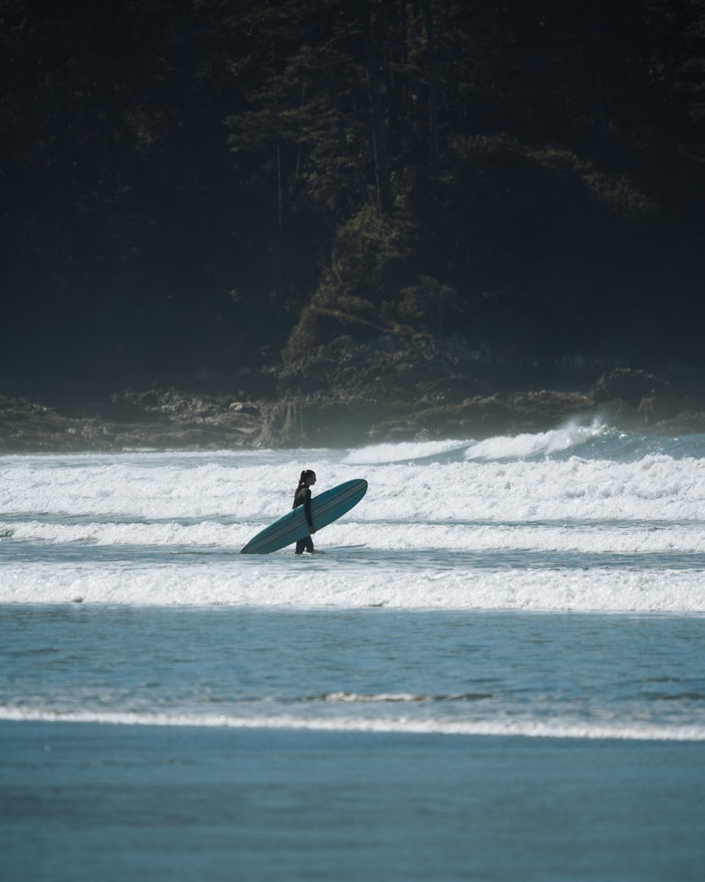 a person walking in the water with a surfboard