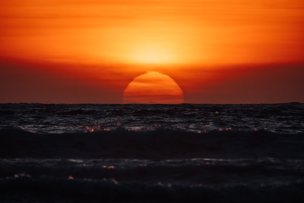 the sun is setting over the ocean with waves