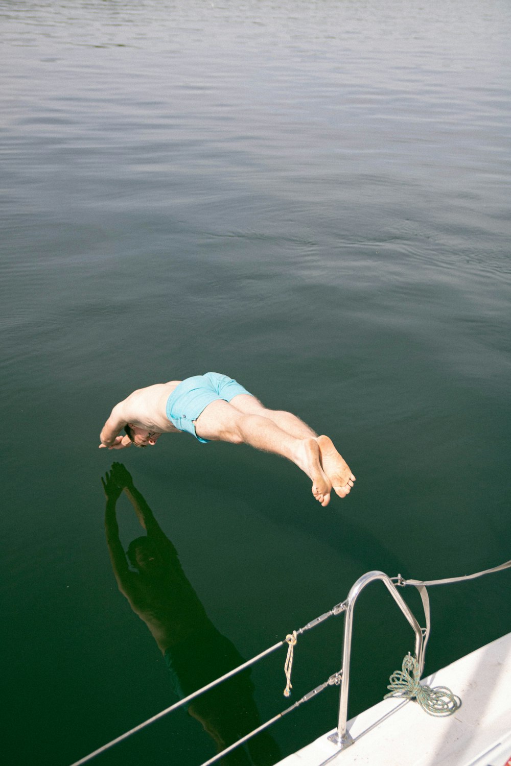 um homem mergulhando na água de um barco