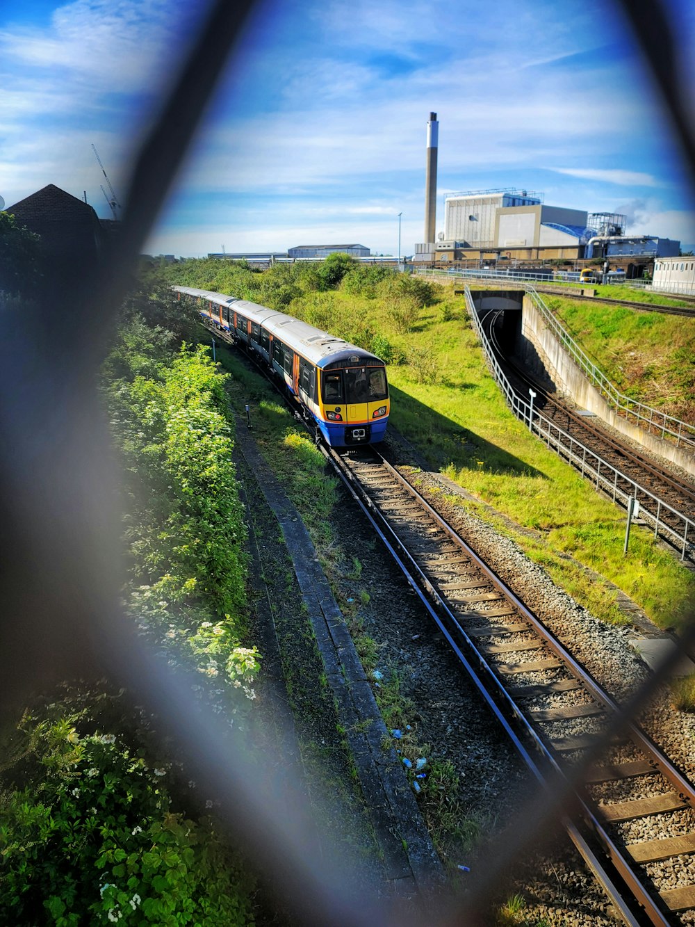 a train traveling down train tracks next to a lush green hillside