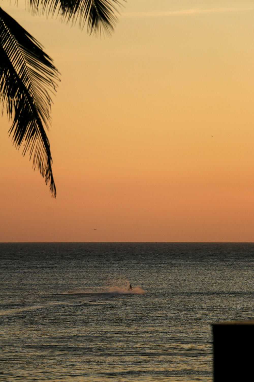 uma pessoa em uma prancha de surf no oceano ao pôr do sol