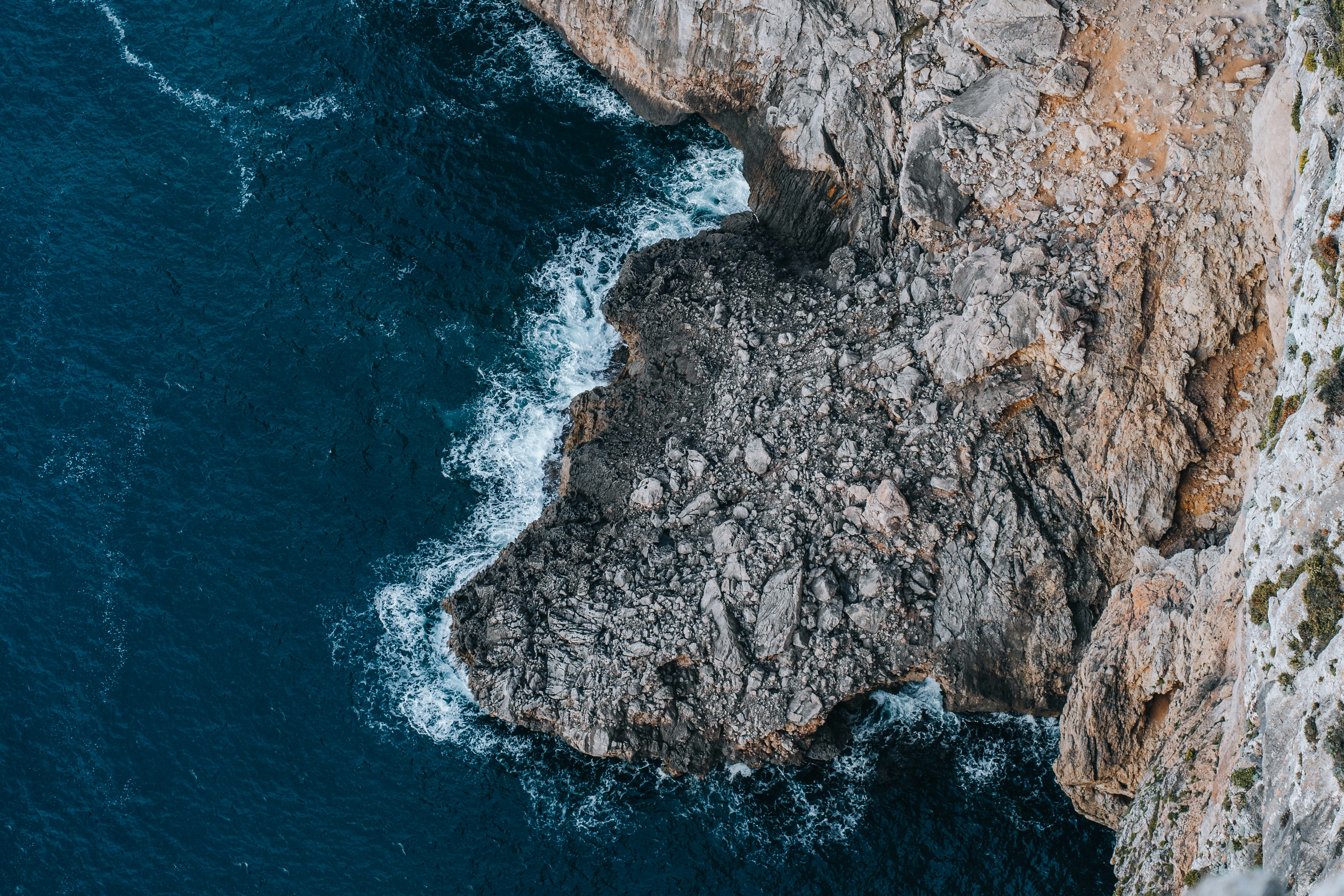 an aerial view of a rocky cliff and the ocean