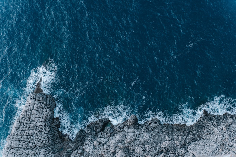 an aerial view of the ocean and rocks