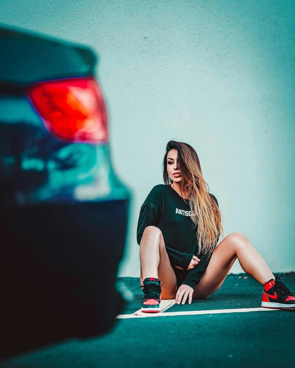 uma mulher sentada no chão ao lado de um carro