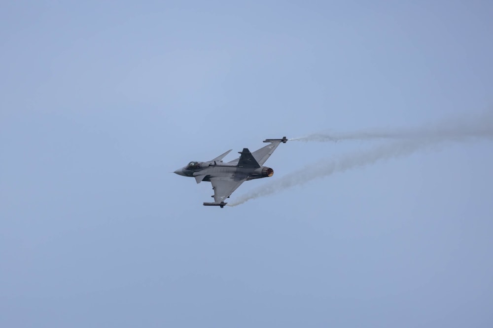 a fighter jet flying through a blue sky