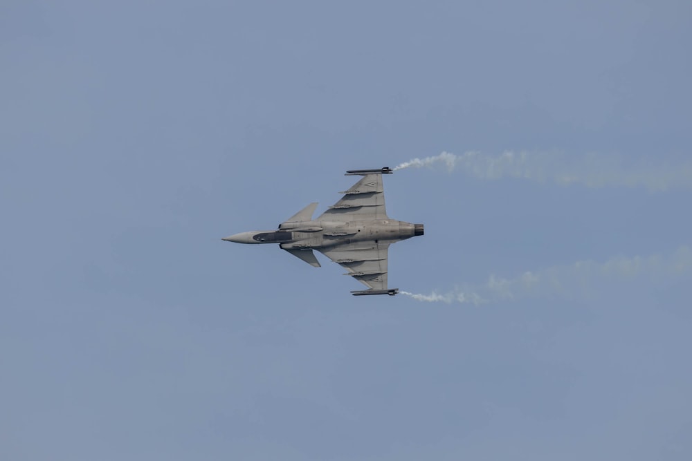 a fighter jet flying through a blue sky