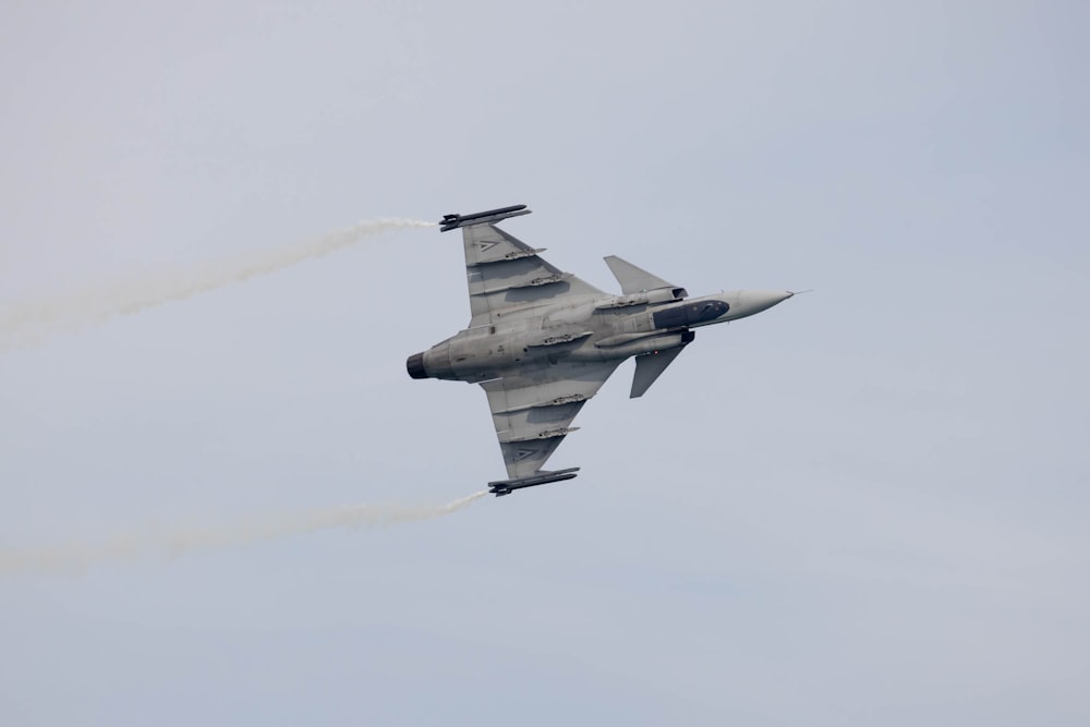 a fighter jet flying through a cloudy blue sky