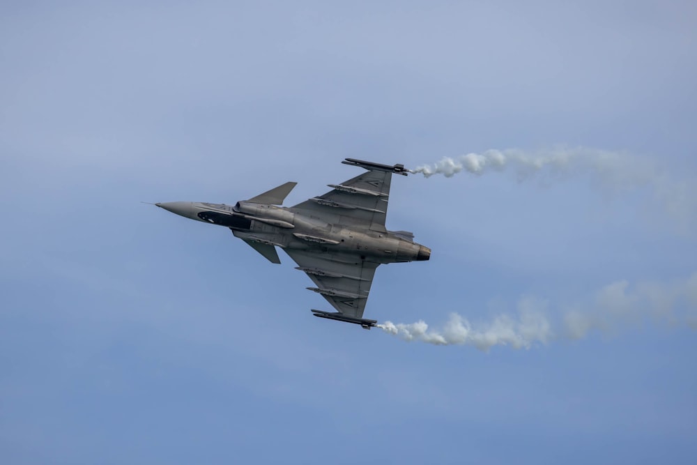 a fighter jet flying through a blue sky