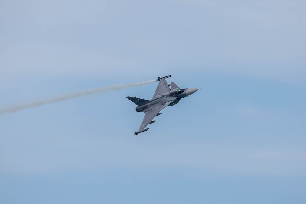 a fighter jet flying through a blue sky