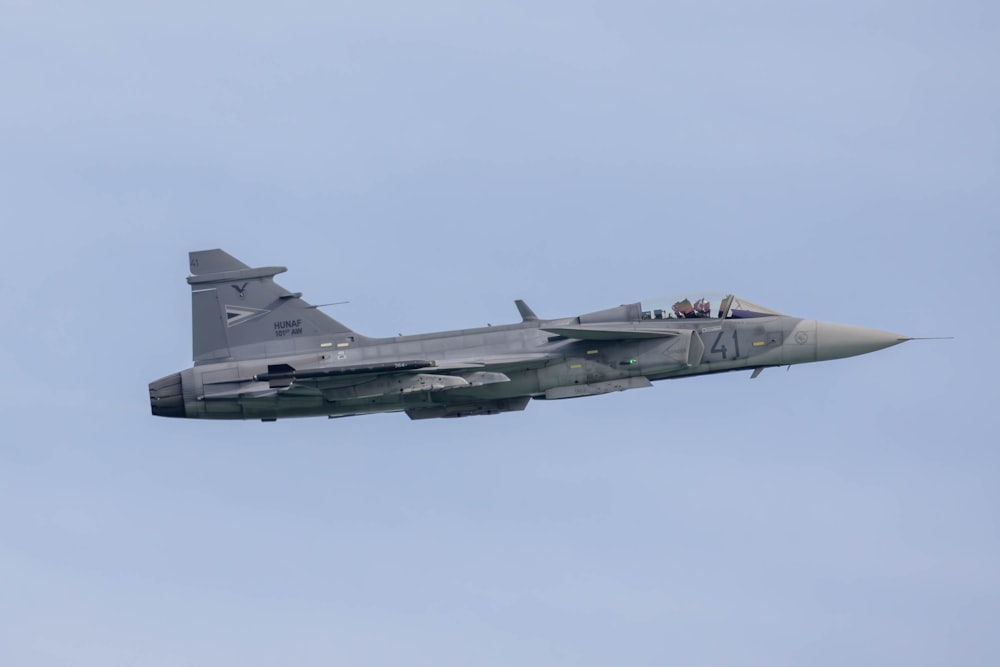 a fighter jet flying through a blue sky