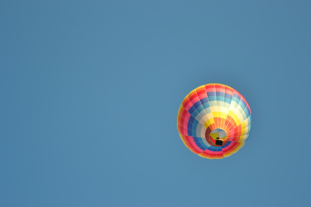 a colorful hot air balloon flying through a blue sky