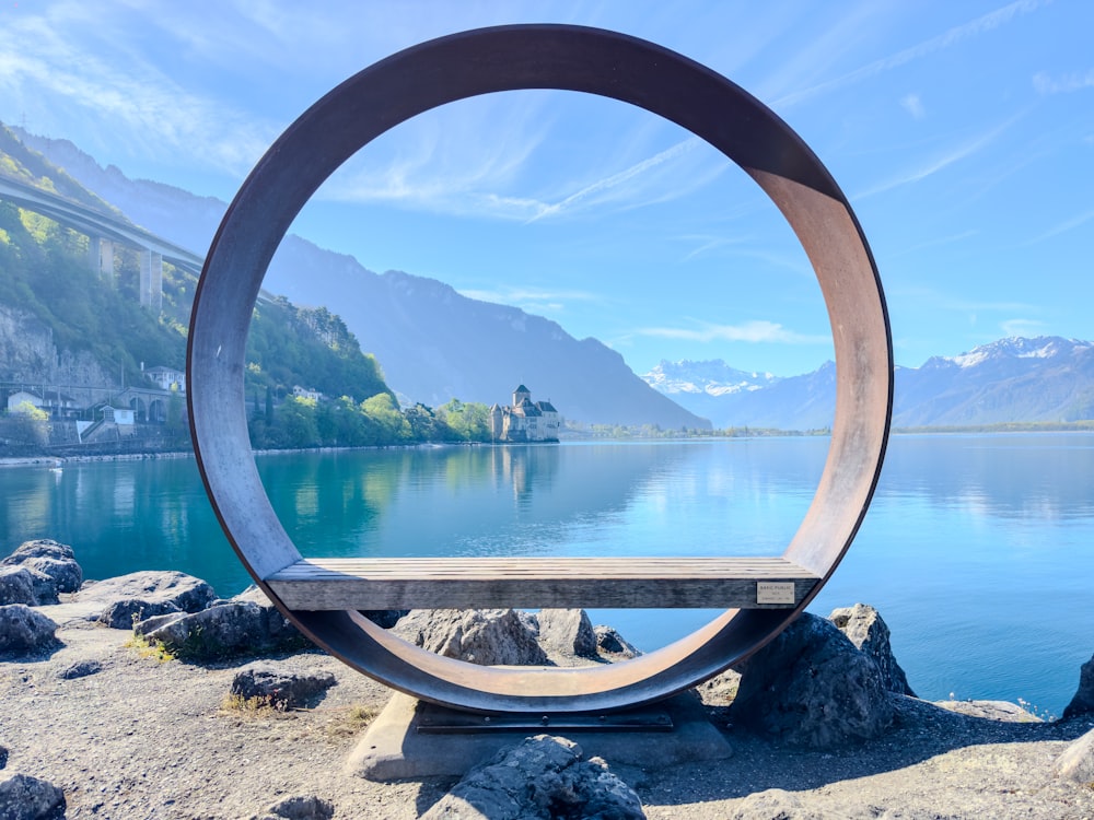 a circular sculpture sitting on top of a rock near a body of water