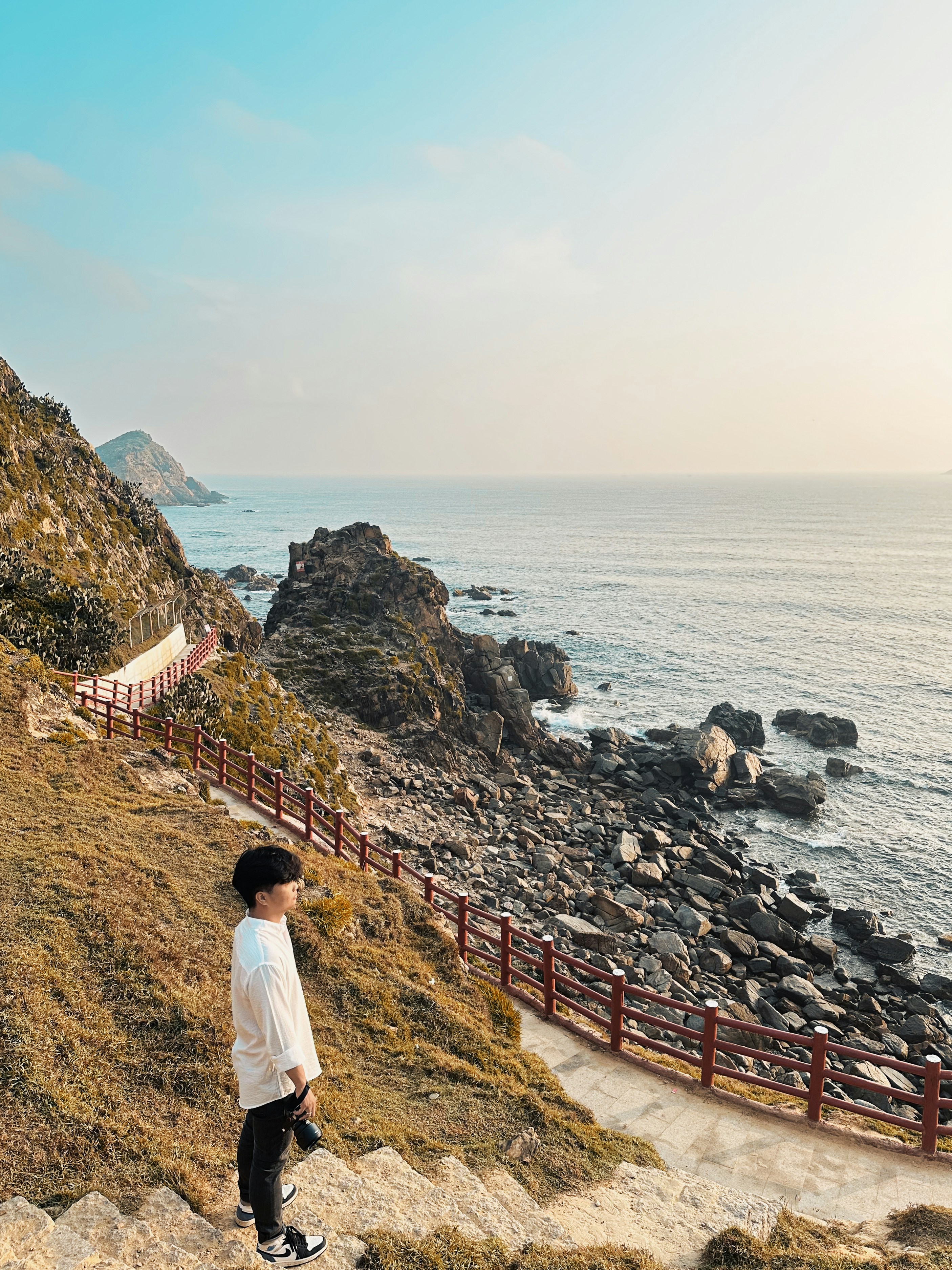 a person standing on a hill next to the ocean