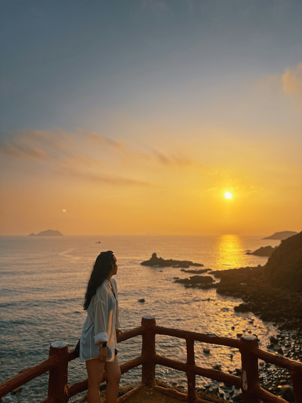 a woman standing on a balcony looking out at the ocean