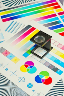 A black linen tester magnifying glass on a CMYK color calibration test chart