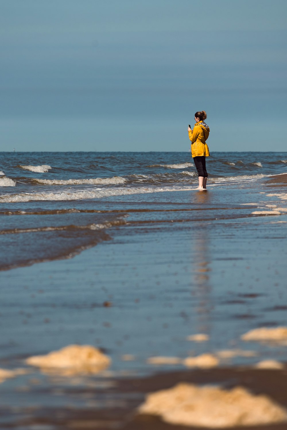 a woman in a yellow jacket standing on a beach