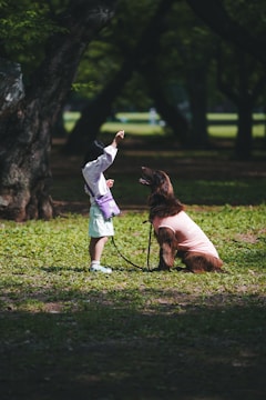 a little girl standing next to a dog on a leash