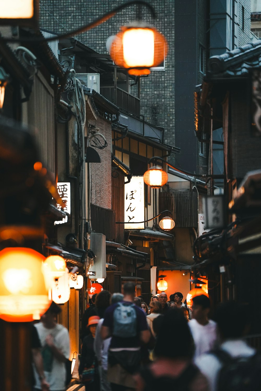 a group of people walking down a street next to tall buildings