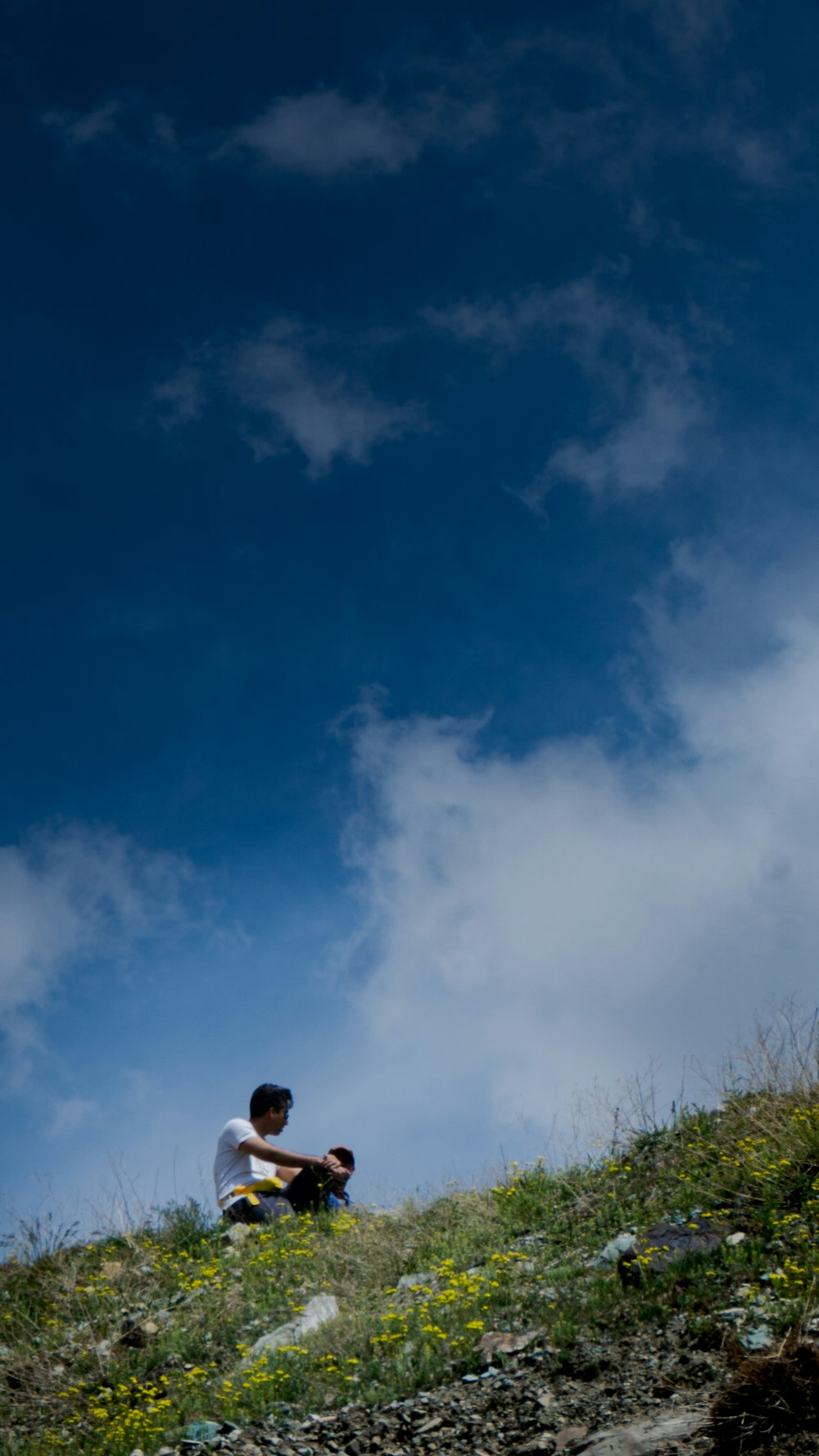 a man sitting on top of a grass covered hillside