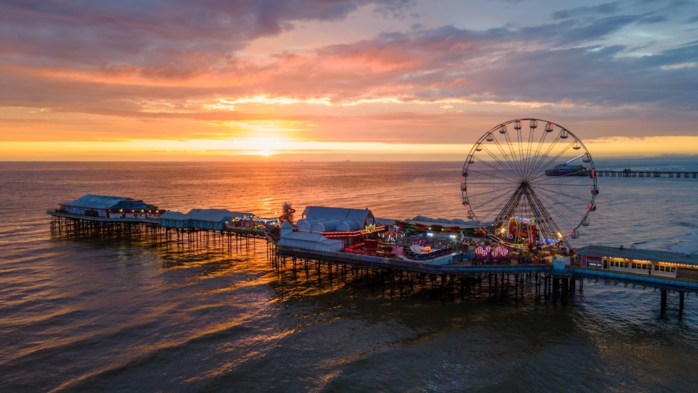 a ferris wheel sitting on top of a pier next to the ocean