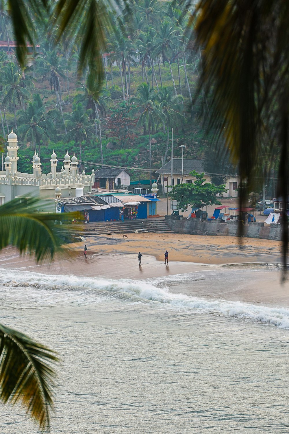 a couple of people standing on top of a sandy beach