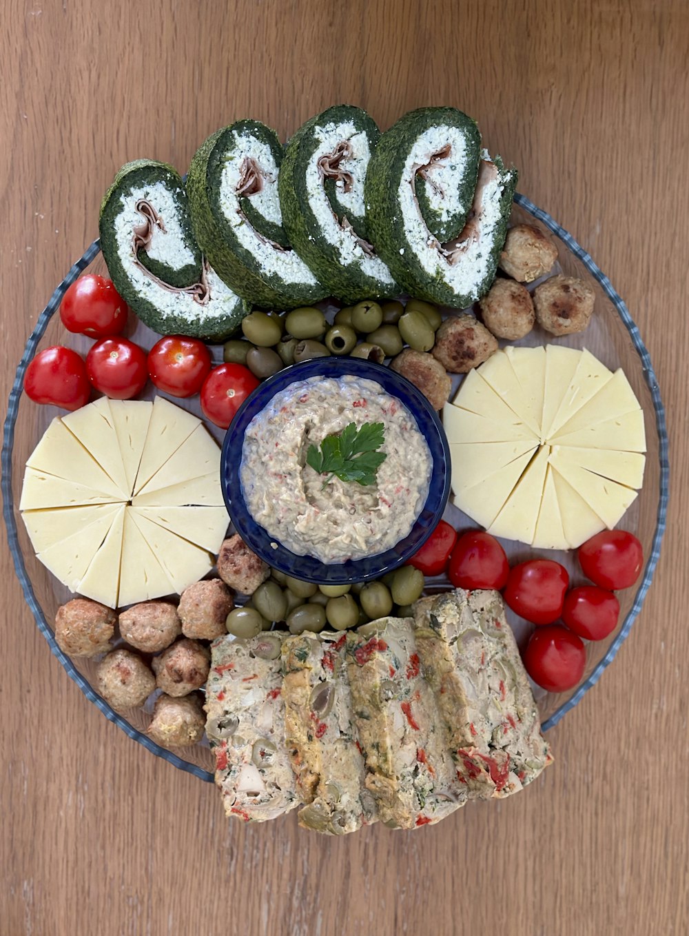 a plate of food that includes crackers, olives, tomatoes, and other