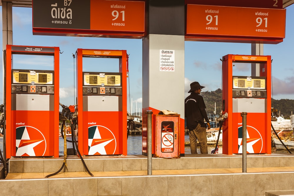 a man standing at a gas station with gas pumps