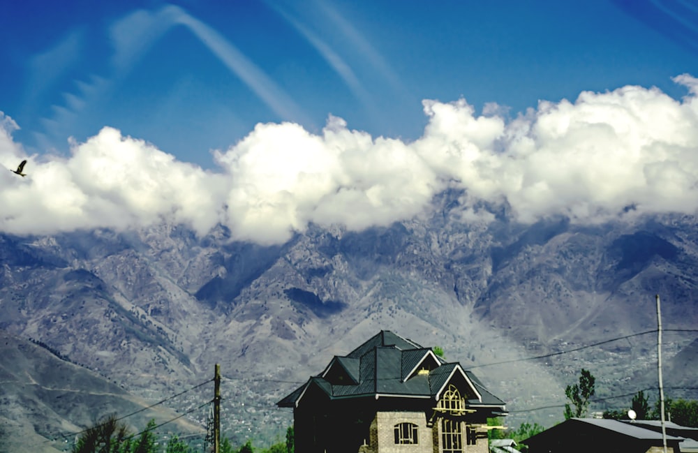 a bird flying over a house in front of a mountain range