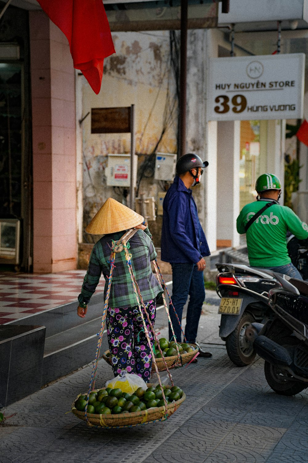 a woman walking down a street carrying a basket of fruit